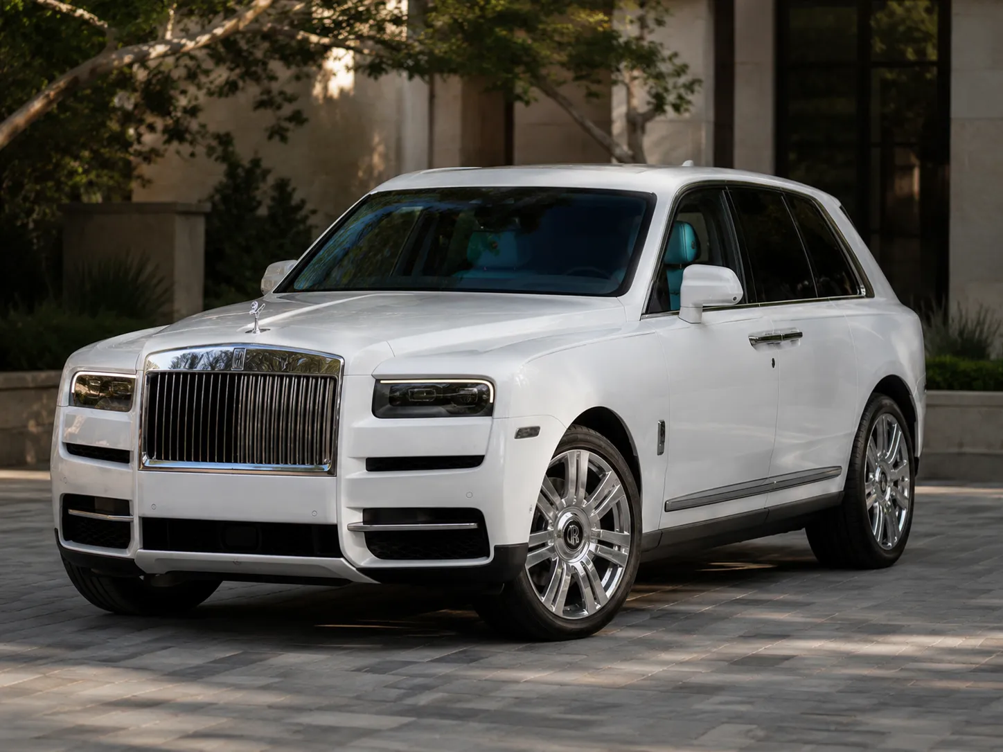 White Rolls-Royce Cullinan parked outside a modern estate
